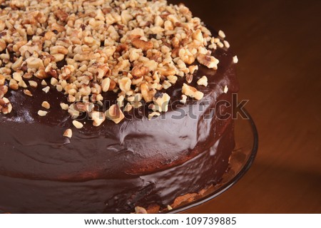 Home made Chocolate cake topped with chopped pecans, on a cake base. Made by a pastry chef.