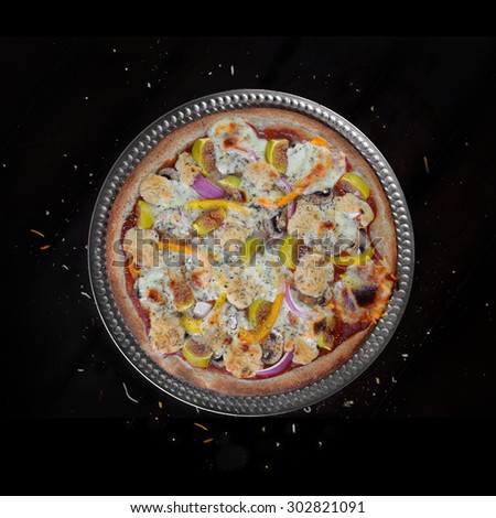 Fresh baked home made veggie pizza with figs and feta cheese over black background
