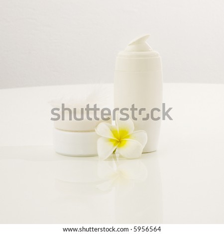 Facial skin cream bottles over white background with tropical flower