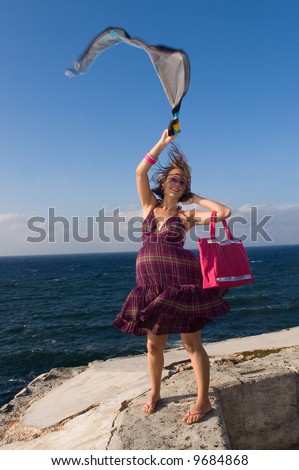 Happy casual girl waving a scarf in ocean background