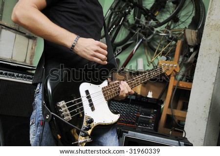 Portrait of man playing electric bass guitar on grunge garage