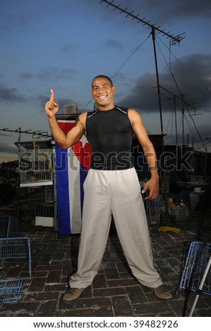 Portrait of african hispanic guy standing with attitude on grunge rooftop with cuban flag