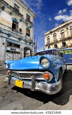 Blue classic american car in havana street with eroded buildings in the background