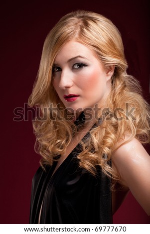 stock photo Perfect blonde in a black dress on red background