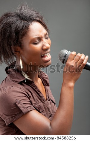 Black Woman Singing Into Microphone , on grey background