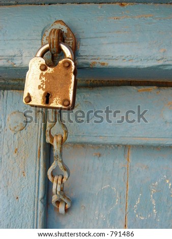 rusty metal door lock with a chained latch on a old blue door