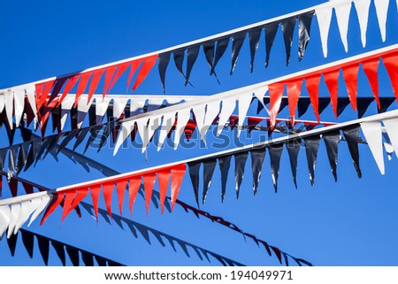 Three strands of festive red, white and black triangular plastic flags (bunting) against a dark blue cloudless sky