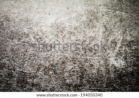 Photographic or artistic abstract texture of grime, dirt, lines and marks on a rough pebbled stucco wall in a car wash