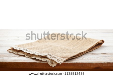 Empty canvas napkin with lace, tablecloth on wooden table on white background. Can used for display or montage your products. Selective fokus