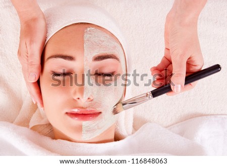 Woman receiving facial mask at beauty salon. macro
