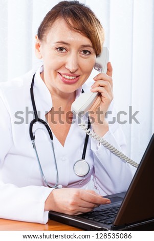 Happy Doctor with Stethoscope Giving Consultation to Patient in Clinic. Woman doctor consults by phone