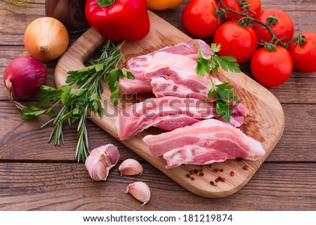 Raw meat for barbecue with fresh vegetables on wooden surface. Food, meat raw steak, beef steak bbq, tomatoes, peppers, spices for cooking meat.