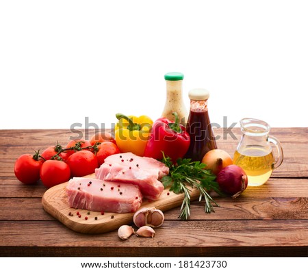 Raw meat for barbecue with fresh vegetables and mushroom wooden surface isolated. Food, meat raw steak, beef steak bbq, tomatoes, peppers, spices for cooking meat. Free space for text.