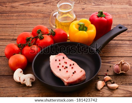 Raw meat for barbecue with fresh vegetables and mushroom wooden surface. Food, meat raw steak, beef steak bbq, tomatoes, peppers, spices for cooking meat. Free space for text.