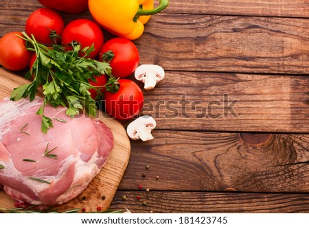 Raw meat for barbecue with fresh vegetables and mushroom wooden surface. Food, meat raw steak, beef steak bbq, tomatoes, peppers, spices for cooking meat. Free space for text.