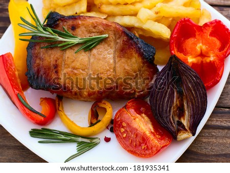 Food.  Meat  barbecue with vegetables on wooden surface. Meat steak. Beef steak bbq. Tomatoes, peppers, spices for cooking meat.
