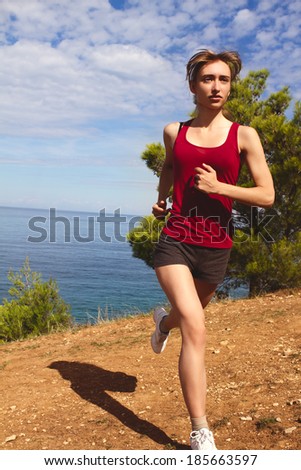 Running woman. Runner jogging in sunny bright light. Summer sea. Female fitness model training. Female runner jogging during outdoor workout on beach.