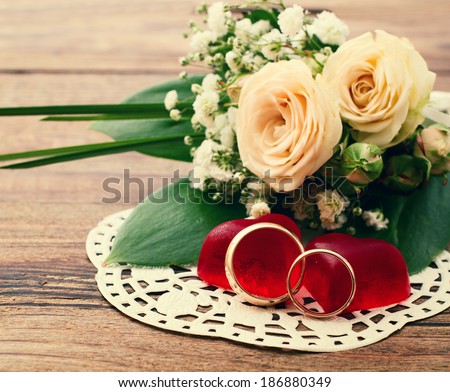 Bridal bouquet of white flowers on wooden surface. Wedding flowers, unusual designer florist bouquet of delicate roses. Wedding rings, couple, heart. Wedding bouquet, background. Empty wooden tabletop