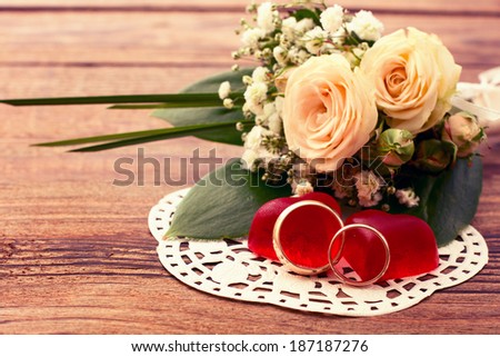 Bridal bouquet of white flowers on wooden surface. Wedding flowers, unusual designer florist bouquet of delicate roses. Wedding rings. Wedding bouquet, background. Empty wooden tabletop