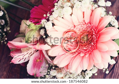 Bridal bouquet of white flowers on wooden surface. Wedding flowers, unusual designer florist bouquet of delicate roses. Wedding rings. Wedding bouquet, background. Empty wooden tabletop