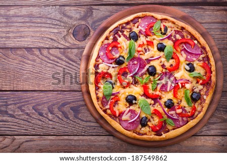 Pizza with ham, pepper and olives. Delicious fresh pizza served on wooden table. Pizza with tomato, salami and olives  Empty wooden tabletop