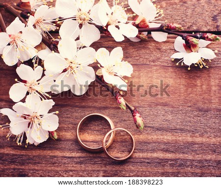 Flowering branch with white delicate flowers on wooden surface. Declaration of love, spring. Wedding card, Valentine\'s Day greeting. Wedding rings. Wedding bouquet, background. Empty wooden tabletop