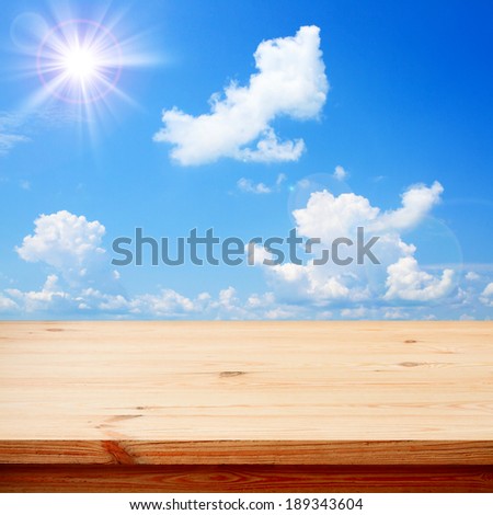 Empty wooden deck table for product montage. Sunny Day, Blue Sky with Clouds Free space for your text