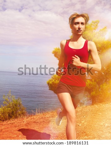 Happy running woman. Runner jogging in sunny bright light. Summer sea. Female fitness model training. Female runner jogging during outdoor workout on beach.