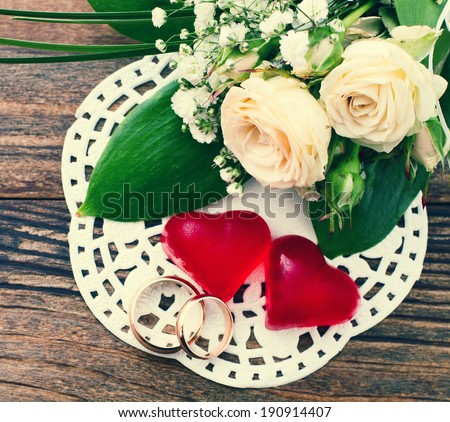 Bridal bouquet of white flowers on wooden surface. Wedding flowers, unusual designer florist bouquet of delicate roses. Wedding rings. Wedding bouquet, background.