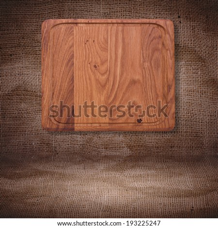 Wooden table covered with checked tablecloth. Empty kitchen cutting board on a background of the tablecloth for product installation. Space for text