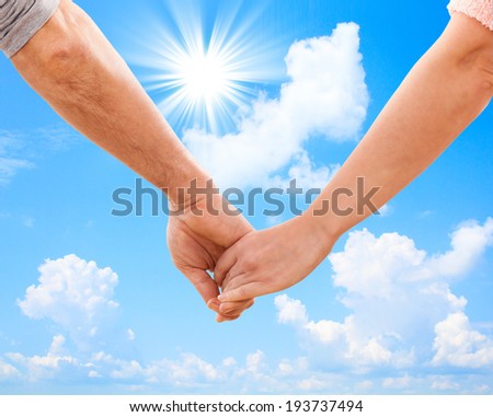 Happy couple holding hands. Blue sky with sun and beautiful clouds