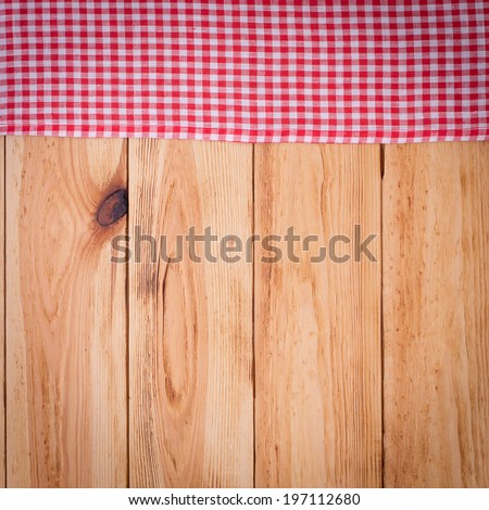 Wood texture background. Pure notebook for recording menu, recipe on red checkered tablecloth tartan. Wooden table close up view from top. Empty wooden deck table with tablecloth for product montage.