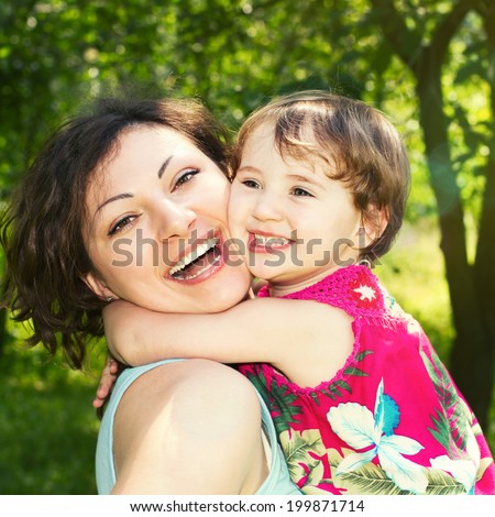 Portrait of a happy little girl who embraces his mother. Face of a beautiful mother and daughter close-up. Outdoor portrait of happy family. Joy mom and baby.