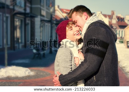 Portrait of young sensual couple in cold winter weather. Love and kiss. Young people. Snow lovers kiss city. Fashion clothing