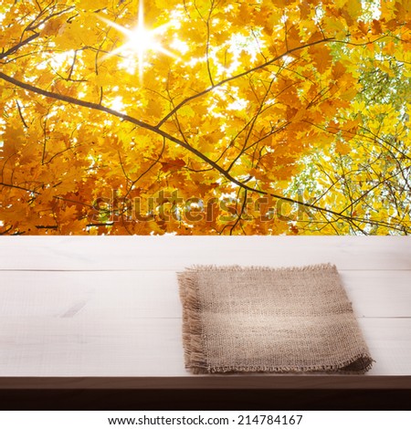 Wooden table covered with tablecloth. View from top. Empty tablecloth for product montage. Pure notebook for recording menu, recipe. Stage for mounting pages. Autumn landscape