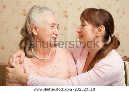 Happy family. Portrait of elderly woman and adult daughter happily looking at camera. Senior  woman with their caregiver at home.