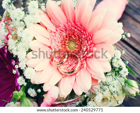 Flowers. Wedding bridal bouquet of white roses and pink lilies with wedding rings on  wooden table, macro
