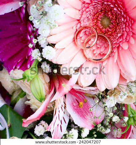 Flowers. Wedding bridal bouquet of white roses and pink lilies with wedding rings on  wooden table, close-up