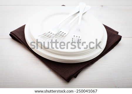 Empty plates and cutlery on the table cloth on a wooden table for dinner. Top view horizontally.