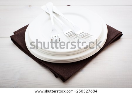 Empty plates and cutlery on table cloth on wooden table for dinner. Top view horizontally.