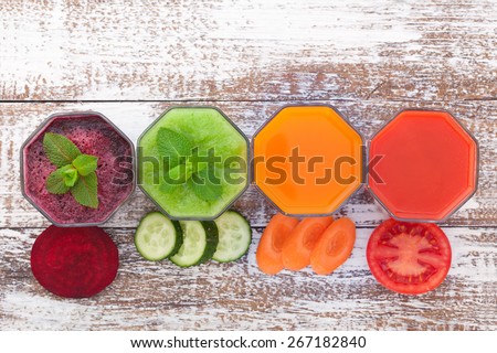 Tomato, cucumber, carrot, beet Juices and vegetables on white wooden table top view.