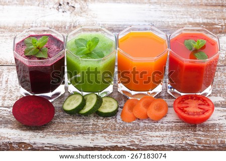 Tomato, cucumber, carrot, beet Juices and vegetables on white wooden table