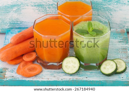Cucumber, carrot Juices and vegetables on white wooden table