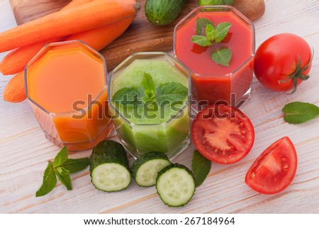 Tomato, cucumber, carrot Juices and vegetables on white wooden table top view