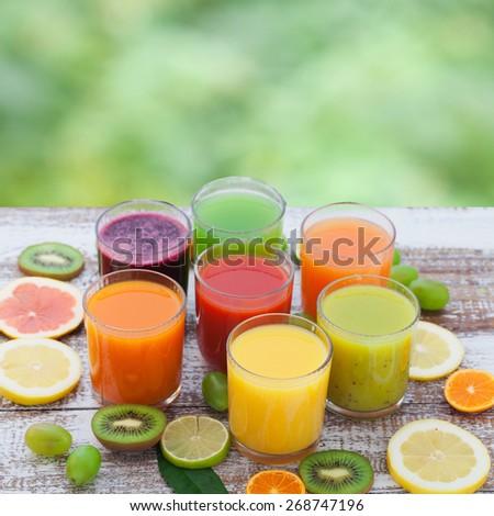 Fruit and vegetable juice in glasses and fresh fruits on wooden table summer background