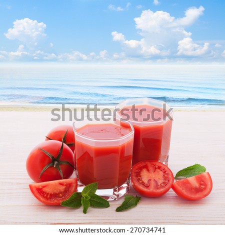 Tomato juice and vegetables on white wooden desk. Panorama of tropical landscape sky, sea, beach