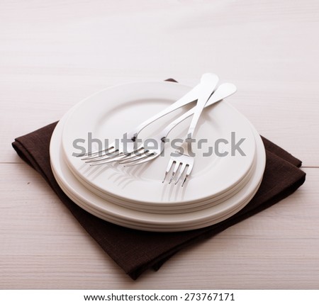Empty plates and cutlery on table cloth on white wooden table for dinner. Square