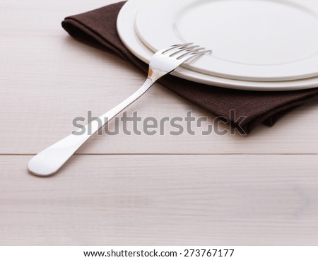 Empty plates and cutlery on table cloth on white wooden table for dinner. Square