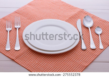 Empty plates and cutlery on table cloth on wooden table for dinner. Top view horizontally. Mock up for design.