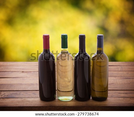 Wine bottles close up on wooden desk. Flat mock up for design. Blurred background.
